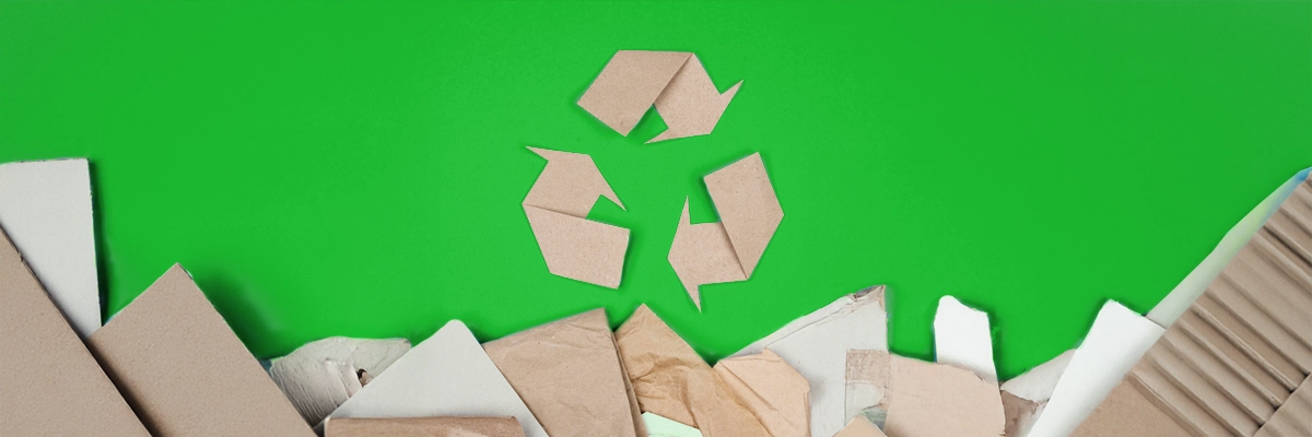 Recycling-Symbol aus Karton über nachhaltigen Verpackungsmaterialien auf grünem Hintergrund im Bereich Fulfillment
