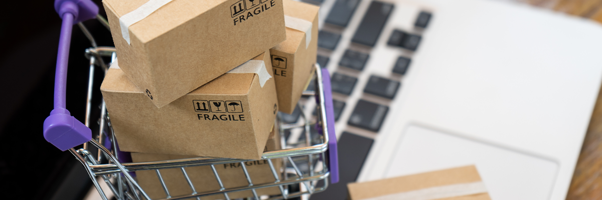 E-Commerce Fulfillment: Pakete im Einkaufswagen vor Laptop als Symbol für Onlinehandel und Versandabwicklung.