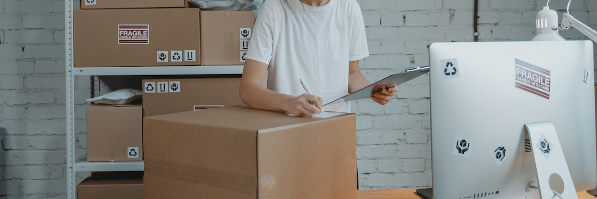Mitarbeiter eines Fulfillment-Dienstleisters kontrolliert Versandkarton im Lager vor dem Versand.