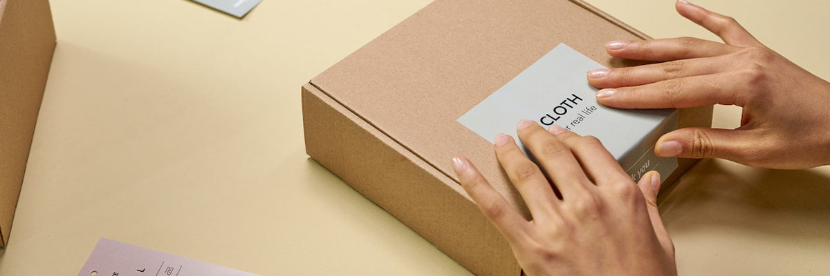 Waren-Konfektionierung für Online-Händler: Karton wird mit Label und Branding für den Versand vorbereitet im Bereich Fulfillment.