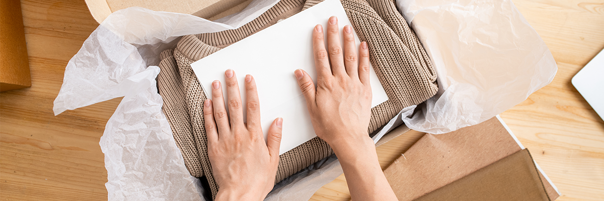 Waren-Konfektionierung im Fulfillment: Kleidung wird mit Einleger und Seidenpapier sorgfältig verpackt.