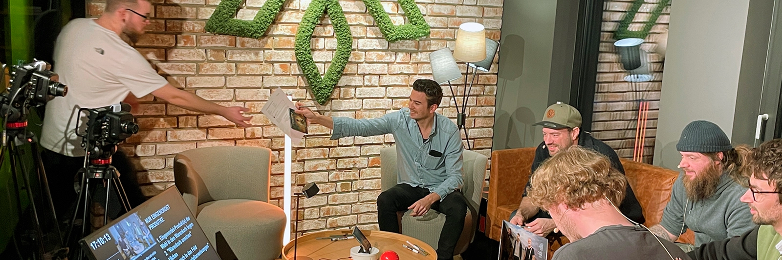 versengold live-event: band im set, kameras laufen; team reicht signiermaterial, lockere stimmung und fan-naehe waehrend der signaturaktion